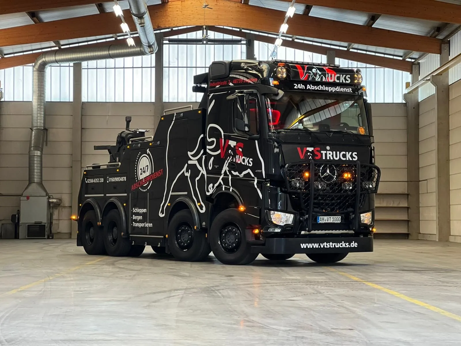 Schwarzes Bergefahrzeug der VTS Trucks GmbH mit Bullen-Grafik in der Halle