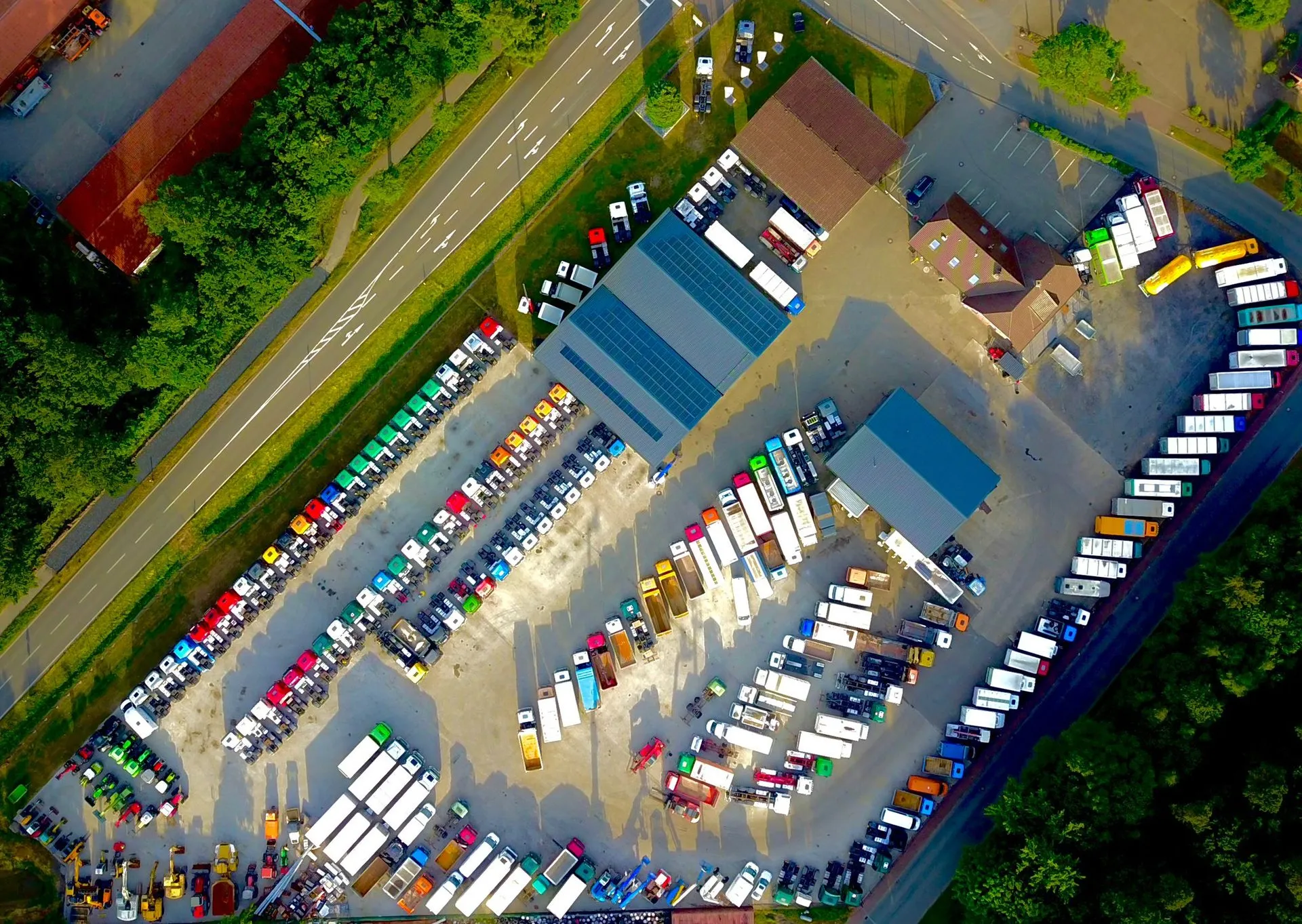 Luftaufnahme des Firmengeländes mit Hallen und abgestellten Lkw und Aufliegern