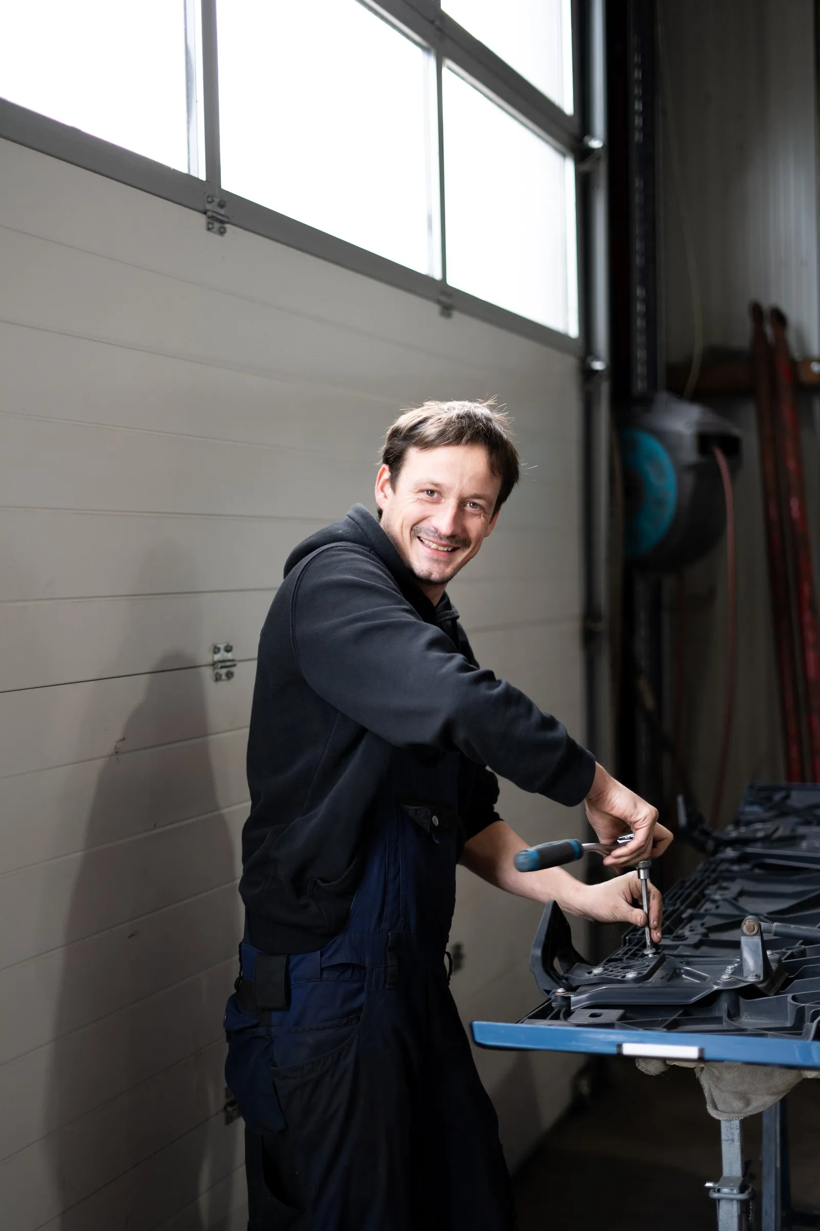 Mechaniker der VTS Trucks GmbH arbeitet lachend an der Werkbank in der Werkstatt