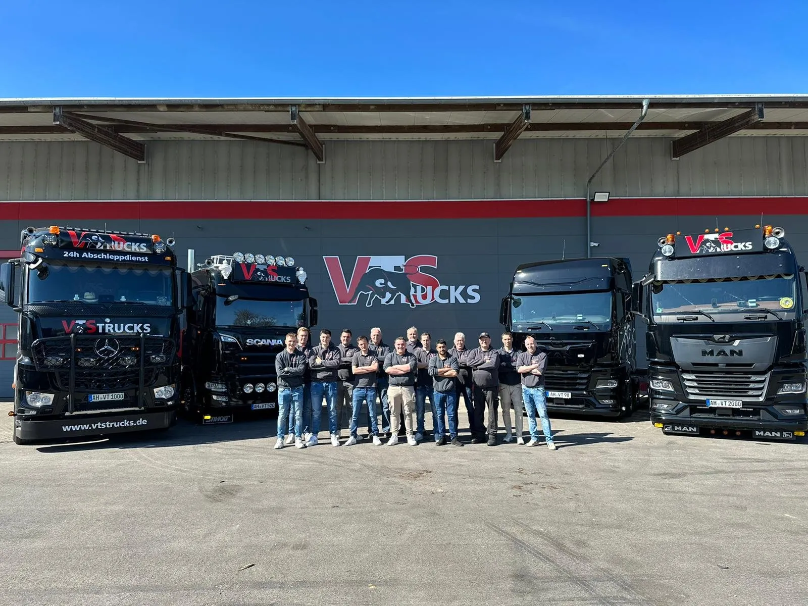 Teamfoto der VTS Trucks GmbH vor mehreren Lkw auf dem Hof