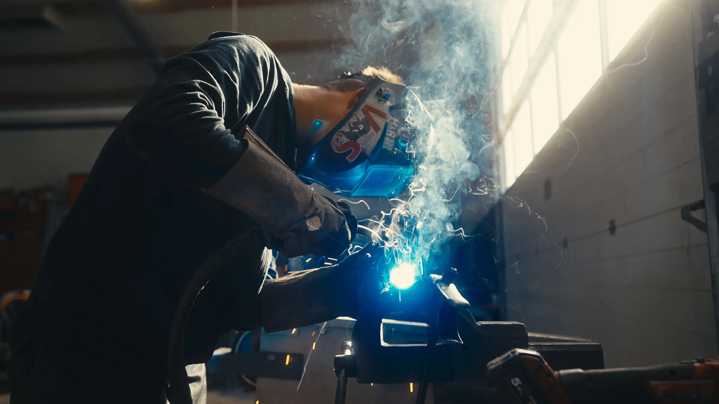 Mitarbeiter mit Schweißhelm bei Schweißarbeiten in der Werkstatt